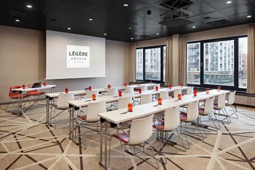 a conference room with tables and chairs and a projection screen at LÉGÈRE HOTEL Bielefeld in Bielefeld