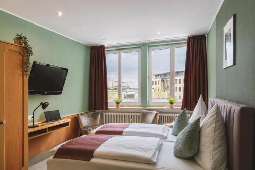 a hotel room with two beds and a television at Hotel Louis Müller in Bitburg