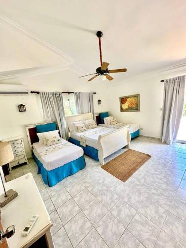 1 dormitorio con 2 camas y ventilador de techo en Amplia Villa en Metro Country Club, en La Puntica de Juan Dolio