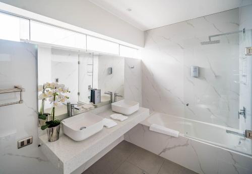 a white bathroom with a sink and a tub at Luxury Ocean View Penthouse with Pool in Miraflores in Lima