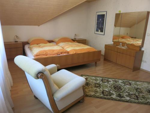 1 dormitorio con cama, silla y espejo en Ferienwohnung Am Teuto, en Tecklenburg