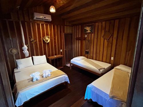 um quarto com 2 camas num chalé de madeira em Vista do Lago Jungle Lodge em Cajual