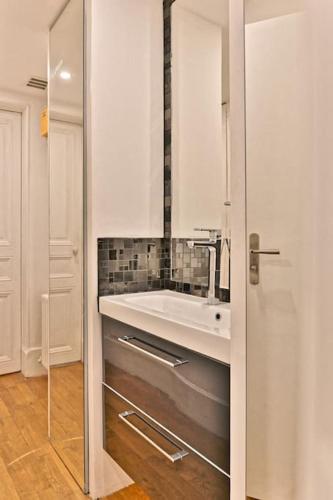 une salle de bain avec un lavabo et un miroir dans l'établissement Agréable Appartement Proche Galerie Lafayette - II, à Paris
