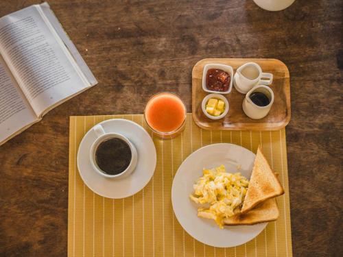 een tafel met een bord ontbijtproducten en een boek bij Bungalows Las Balsas in Máncora
