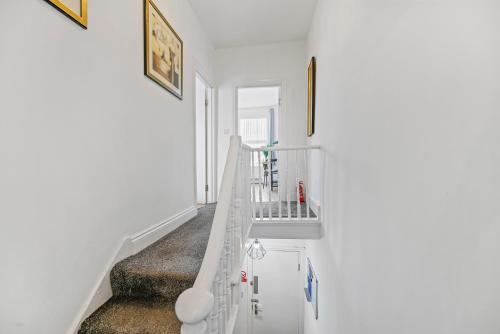 Una escalera blanca en una habitación blanca con lavabo en Cosy Urban Oasis 2 Bedroom Flat in Tottenham ( Sleeps 5 People ) en Londres