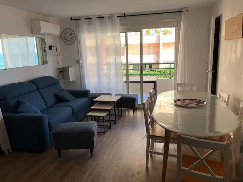 un salon avec un canapé bleu et une table dans l'établissement Appt 8 pers / garage / terrasse / vue mer, à Sète