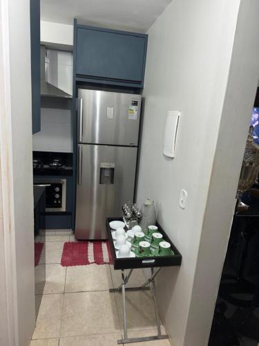 a kitchen with a table with cups and a refrigerator at ALUGUEL TEMPORADA TECNOSHOW in Rio Verde