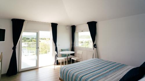 a bedroom with a bed and a table and a balcony at LIDO DEL FARO in Olbia