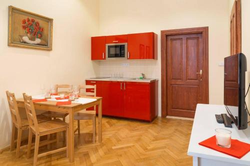 Stella apartments في براغ: مطبخ مع طاولة خشبية ودواليب حمراء