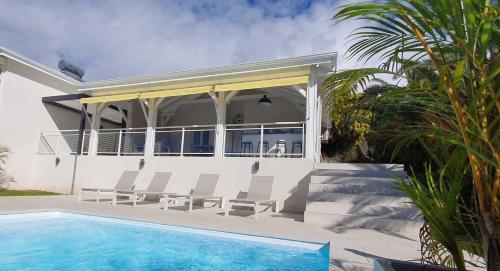 ein Haus mit einem Pool und zwei Stühlen in der Unterkunft Villa Blue Marine in Deshaies