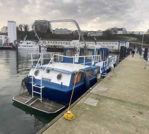 a blue and white boat is docked at a dock at Stahlschiff DORINA in Sassnitz