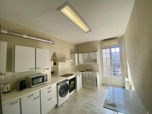 une cuisine avec des armoires blanches et une laveuse et une sécheuse dans l'établissement Grand F3- Centre ville de Nice, Wifi AC, à Nice
