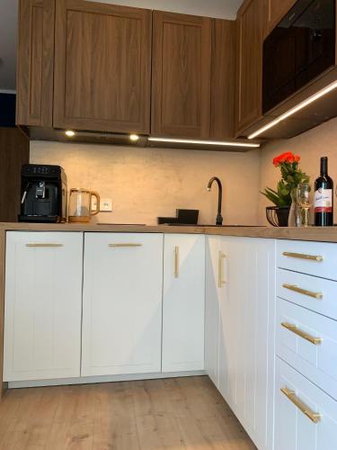 a kitchen with white cabinets and a sink at Apartamenty Piaskowe z balkonem in Rowy