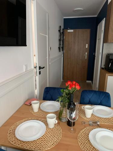 a dining room table with plates and flowers on it at Apartamenty Piaskowe z balkonem in Rowy