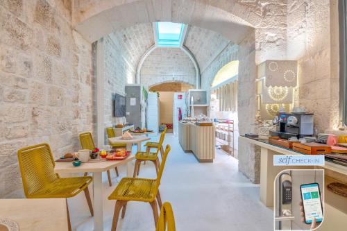 uma cozinha com cadeiras e mesas amarelas num quarto em Vico Bianco Raro Villas Smart Rooms Collection em Ostuni