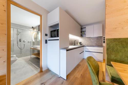 una cucina con armadi bianchi, lavandino e doccia di Rienz Alpine City Suites a Brunico