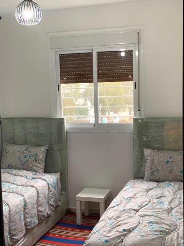 a bedroom with two beds and a window at cozy appartement meublé in Tangier