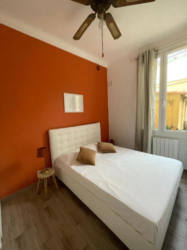 une chambre avec un lit blanc avec un mur orange dans l'établissement Luciana Cannes avec parking - proximité centre croisette -gare -plage, à Cannes