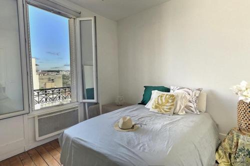 une chambre avec un lit et une grande fenêtre dans l'établissement Boulogne 2 pièces de charme au dernier étage sur jardin., à Boulogne-Billancourt