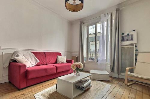 un salon avec un canapé rouge et une table dans l'établissement Boulogne 2 pièces de charme au dernier étage sur jardin., à Boulogne-Billancourt