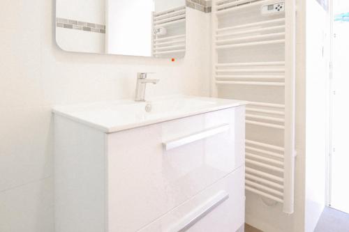 Un baño blanco con lavabo y espejo. en Grand studio face mer Les Sables d'Olonne 4 personnes, en Les Sables-dʼOlonne