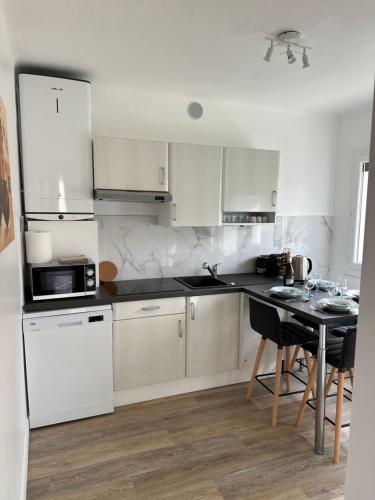 une cuisine avec des appareils blancs et une table avec des chaises dans l'établissement Appartement Cannes, à Cannes