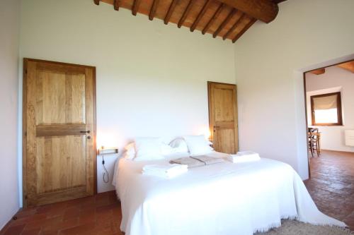 a bedroom with a white bed and two wooden doors at Marrucheti 82 in Campagnatico