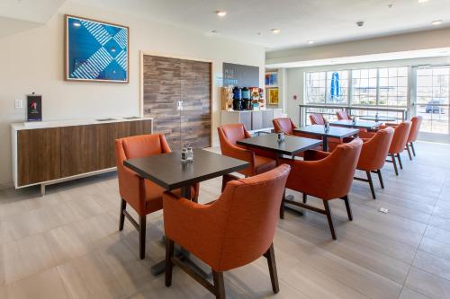 uma sala de jantar com mesas e cadeiras laranja em Holiday Inn Express & Suites Englewood - Denver South, an IHG Hotel em Englewood