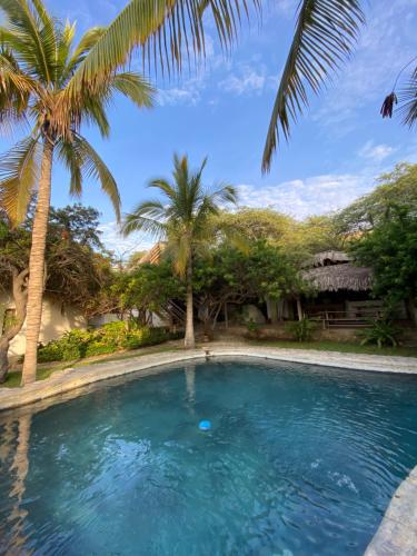 una piscina di fronte a una casa con palme di Bungalows Las Balsas a Máncora