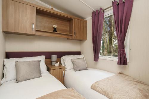 2 Betten in einem kleinen Zimmer mit Fenster in der Unterkunft BUNNY - 3 Bed Static Caravan in Port Seton