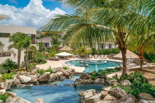 a resort pool with rocks and a palm tree at Jan Sofat LUX A5 in Willemstad