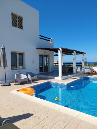 a swimming pool in front of a house at Villa Enalia Paphos in Paphos