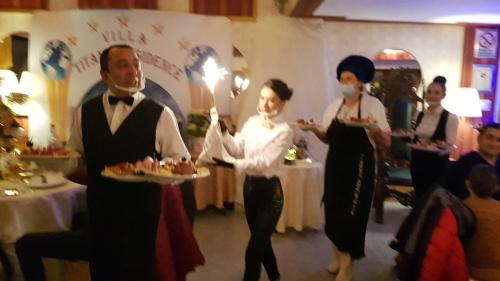 Villa Titanic Residence Spa في أَزوغا: مجموعة أشخاص واقفين في غرفة بها أطباق من الطعام