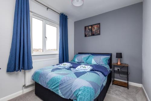 a bedroom with a bed with blue curtains and a window at Leeds 3 Bed 2 - Off Road Parking, Self Check-in, Fast Wi-Fi, Table Football - Families, Contractors, Long Stays in Bramley