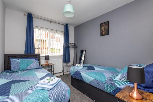 Leeds 3 Bed - Parking, Self Check-in, En-suite, WiFi, Fussball, Garden - Groups, Contractors, Families, Long Stays - Alt-Stay في Bramley: سريرين في غرفة نوم مع ستائر زرقاء
