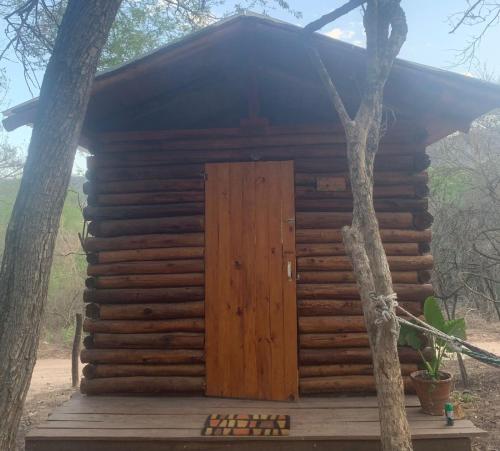 a wooden cabin with a door in the middle of two trees at El Paraíso Ecolodge in Coronel Moldes