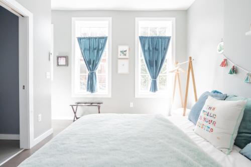 a white bedroom with blue curtains and a bed at Pastel Paradise - Adorable Covington Apartment in Covington