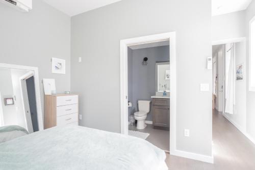 ein weißes Schlafzimmer mit einem Bett und einem Badezimmer in der Unterkunft Pastel Paradise - Adorable Covington Apartment in Covington