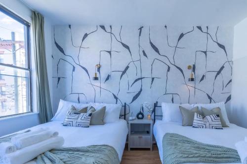 two beds in a bedroom with a tree mural on the wall at Posh Suite with 2 Queen Beds, Full Kitchen, Sleeps 6, by Train, 15 min to NYC in Hoboken