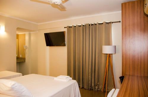 a hotel room with a bed and a television at Hotel Zé Maria in Pouso Alegre