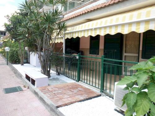 a building with a green fence next to a sidewalk at Casa Vacanza Giardini Naxos Taormina MIRANAXOS in Giardini Naxos