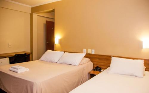 a hotel room with two beds with white pillows at Hotel Zé Maria in Pouso Alegre