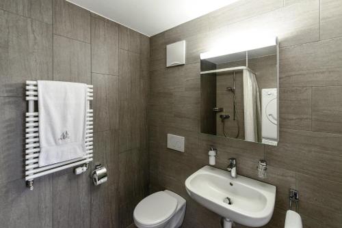 a bathroom with a sink and a toilet and a mirror at RELOC Serviced Apartments Zurich-Oerlikon in Zurich