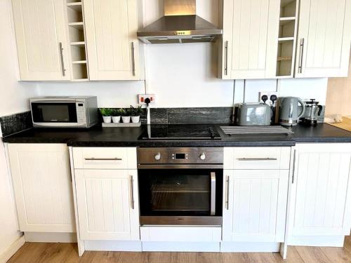 een keuken met witte kasten en een fornuis met oven bij Cosy Apartment Studio Close to Cafes in Norwich