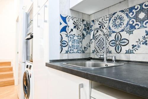 uma cozinha com lavatório e azulejos azuis e brancos em For You Rentals Acogedor Apartamento de Dos Dormitorios en Madrid HDB12 em Madri