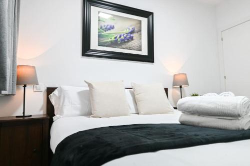uma cama branca com almofadas brancas e uma fotografia na parede em For You Rentals Acogedor Apartamento de Dos Dormitorios en Madrid HDB12 em Madri