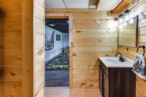 a bathroom with wooden walls and a sink and a mirror at Lock Haven Cabin with Wood Stove and Mountain View! in Lock Haven