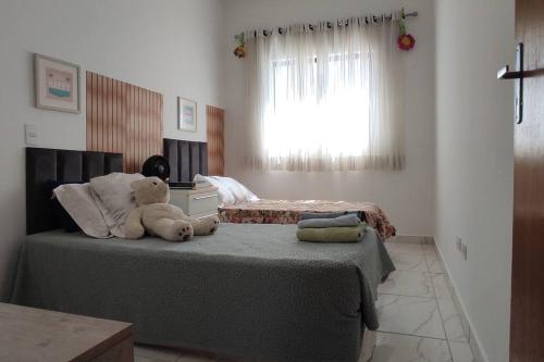 un osito de peluche sentado en una cama en un dormitorio en novinha, aconchegante e moderna! en Londrina
