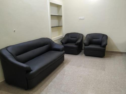 Dos sillas negras y un sofá en una habitación en Anithaas Cottage, en Kuttālam