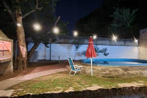 a chair and an umbrella next to a swimming pool at night at Casa familiar estilo colonial a metros del lago in San Bernardino